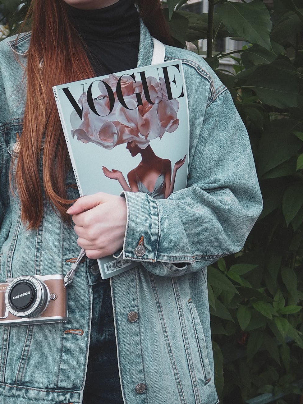 woman in denim jacket holding a magazine